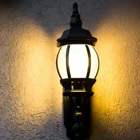 Outdoor wall lantern illuminating a textured surface, highlighting electrical safety and home aesthetics.