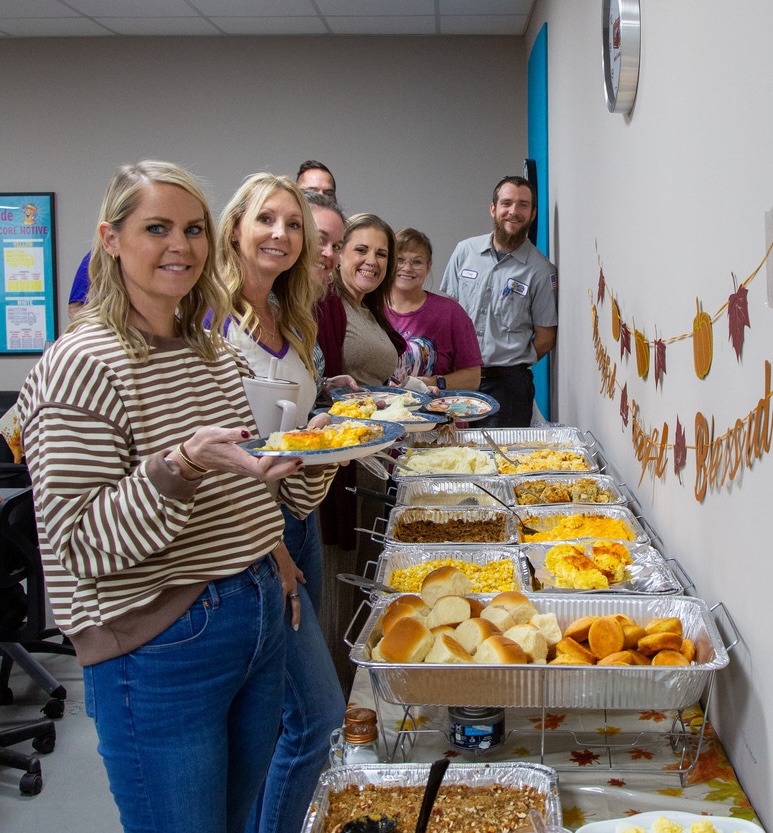 Thanksgiving office party at Keep Smiling Plumbing Electric Heating and Cooling, featuring employees enjoying a buffet of festive foods and celebrating together.
